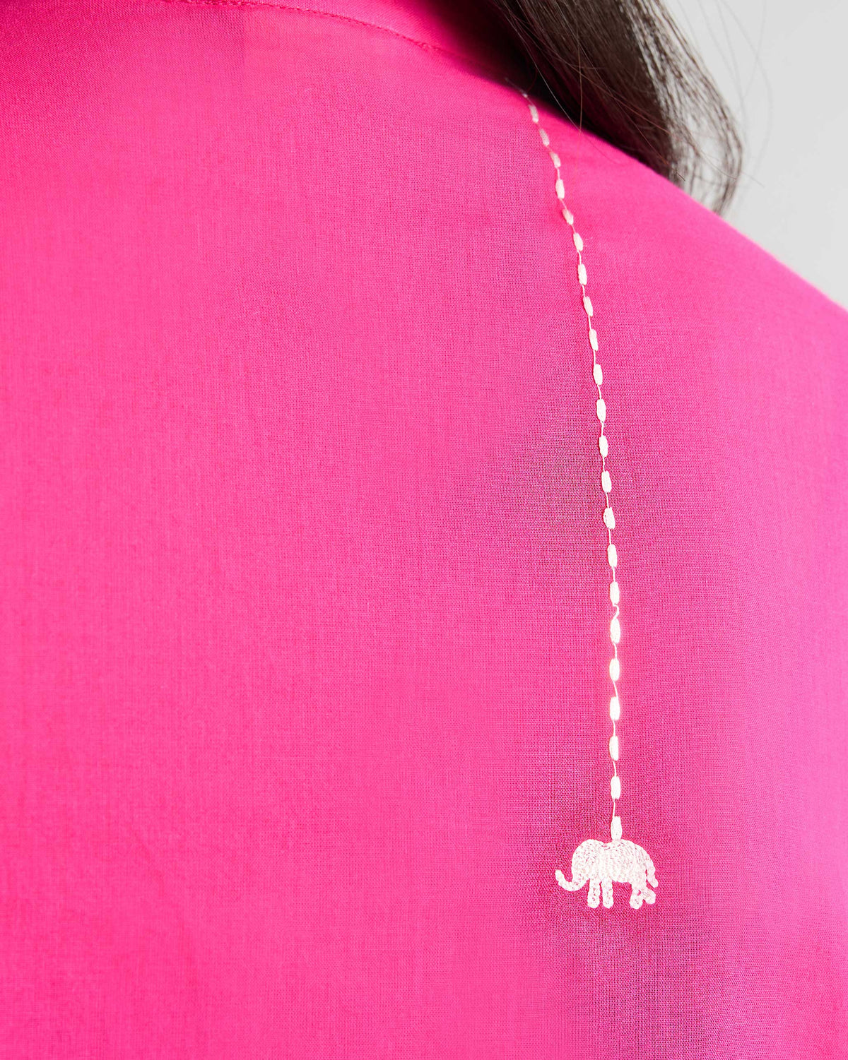 Close-up of a white embroidered elephant on a fuchsia kurta.