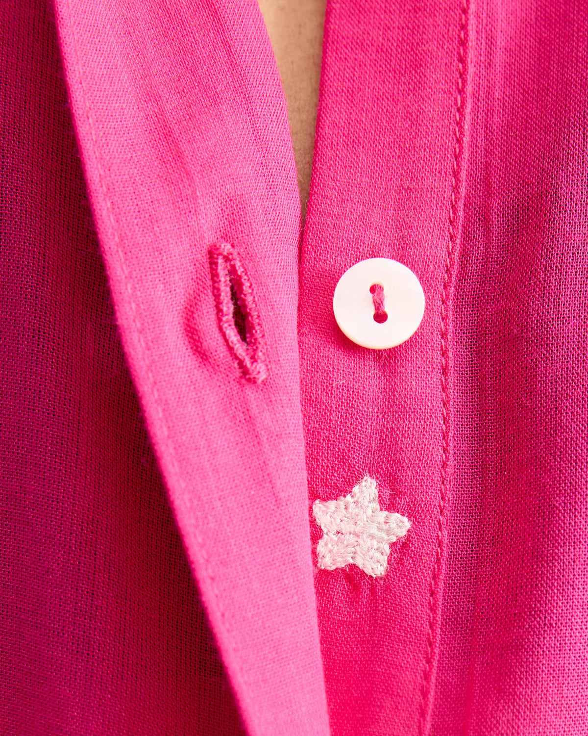 Close-up of a white embroidered star on the placket of a fuchsia kurta.