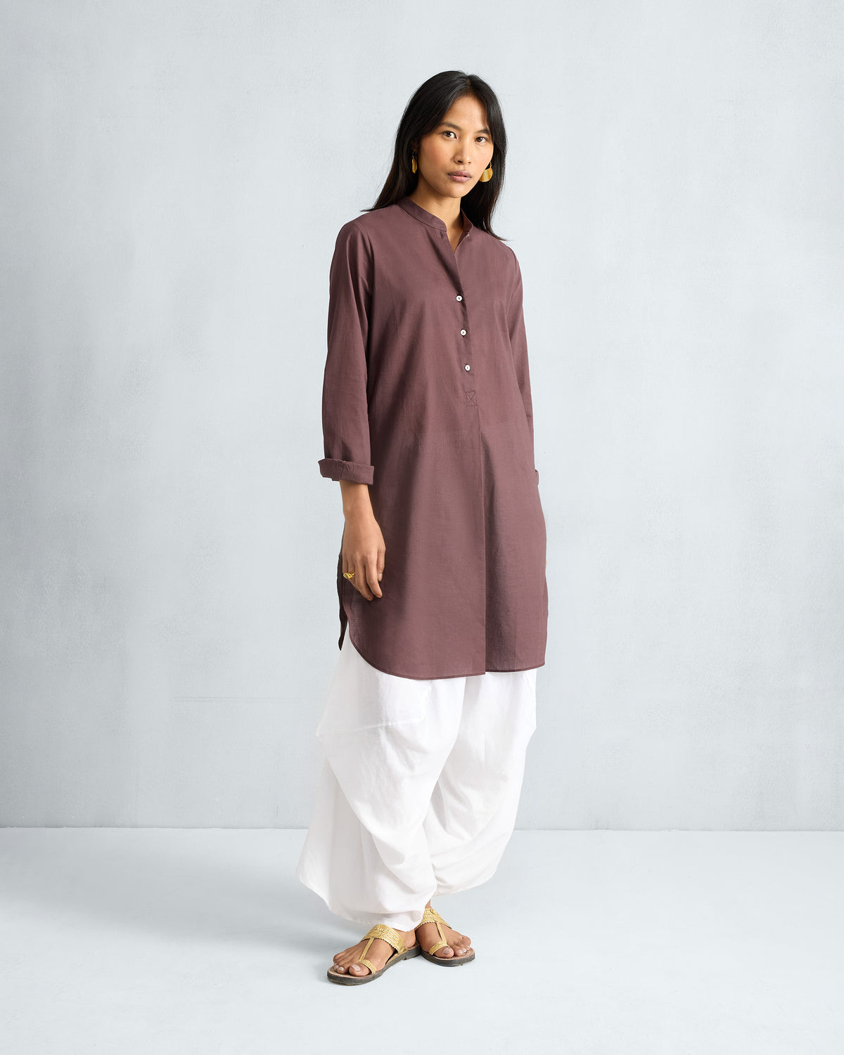 Person wearing a chocolate plum mid-length kurta with rolled sleeves.