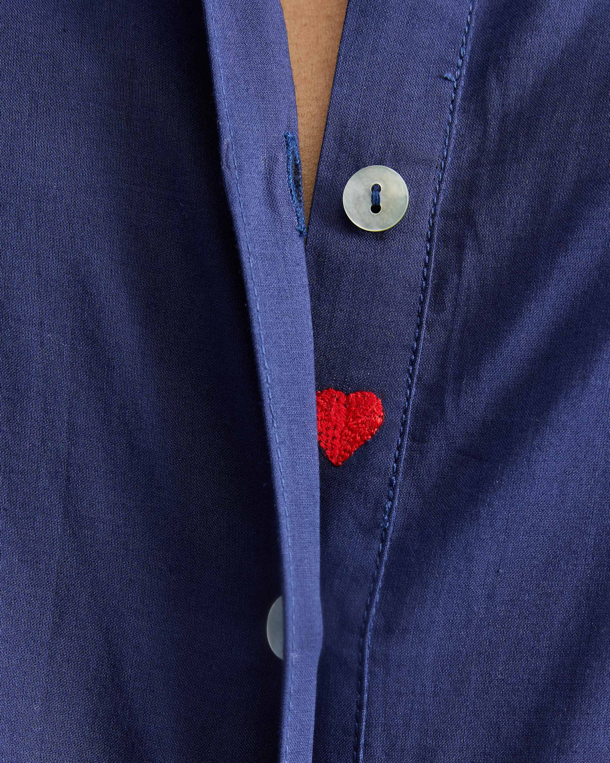 Close-up of a red embroidered heart on the placket of an ink blue kurta.