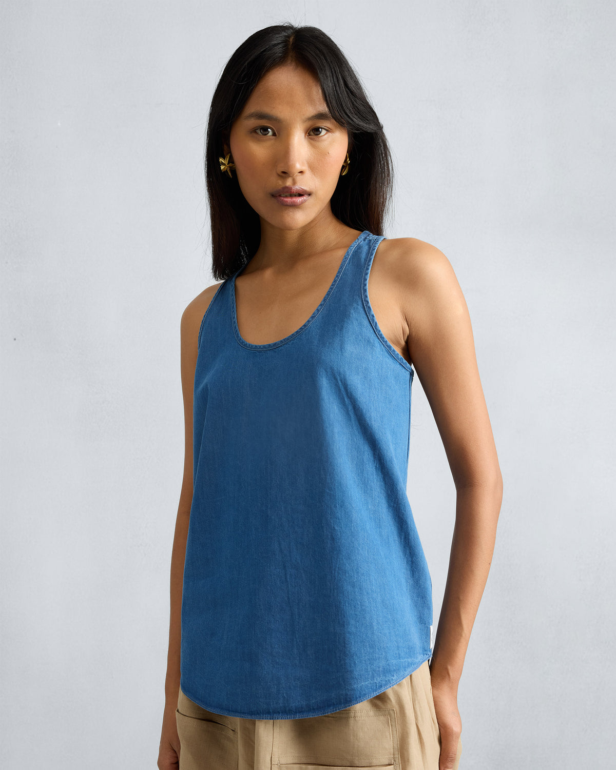 Person wearing a denim Ukiyo racerback tank with a scoop neck.