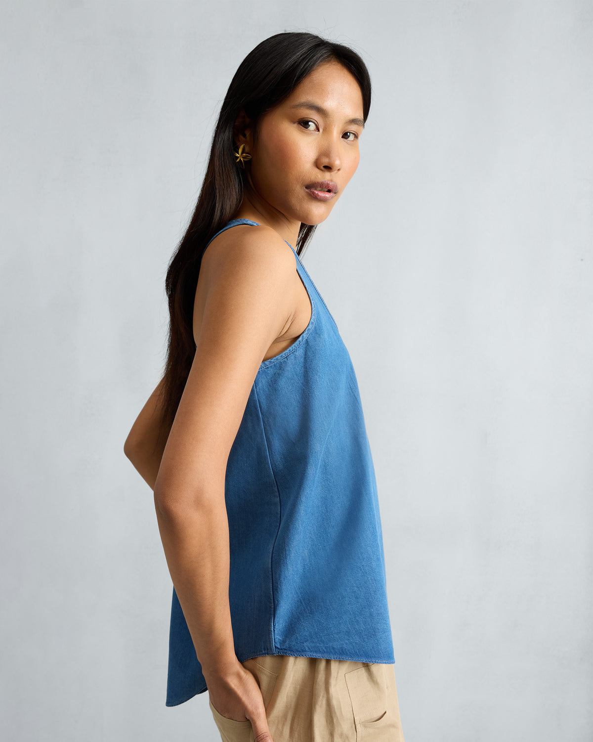 Side view of a denim Ukiyo racerback tank showing the curved hem.