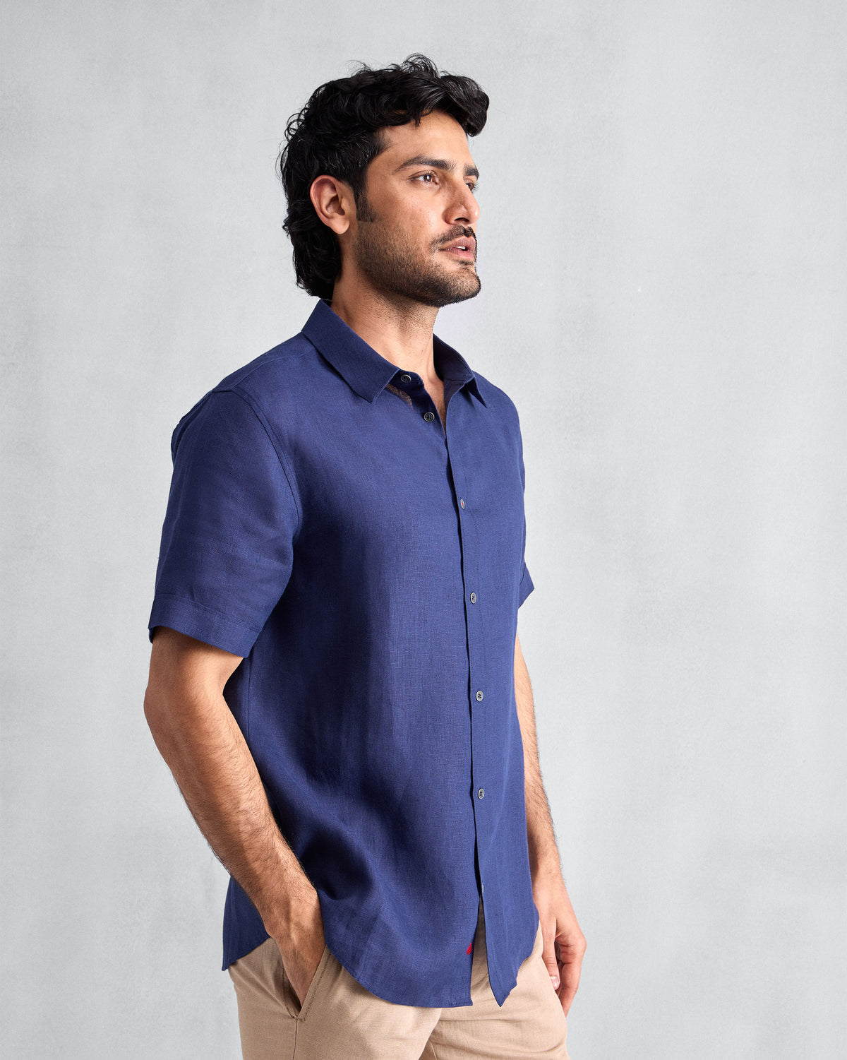 Person wearing an ink blue half-sleeve shirt over beige trousers.