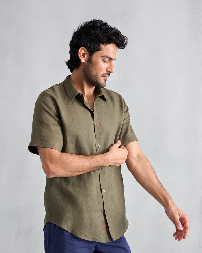 Olive half-sleeve linen shirt with grey buttons and a small red hem embroidery.