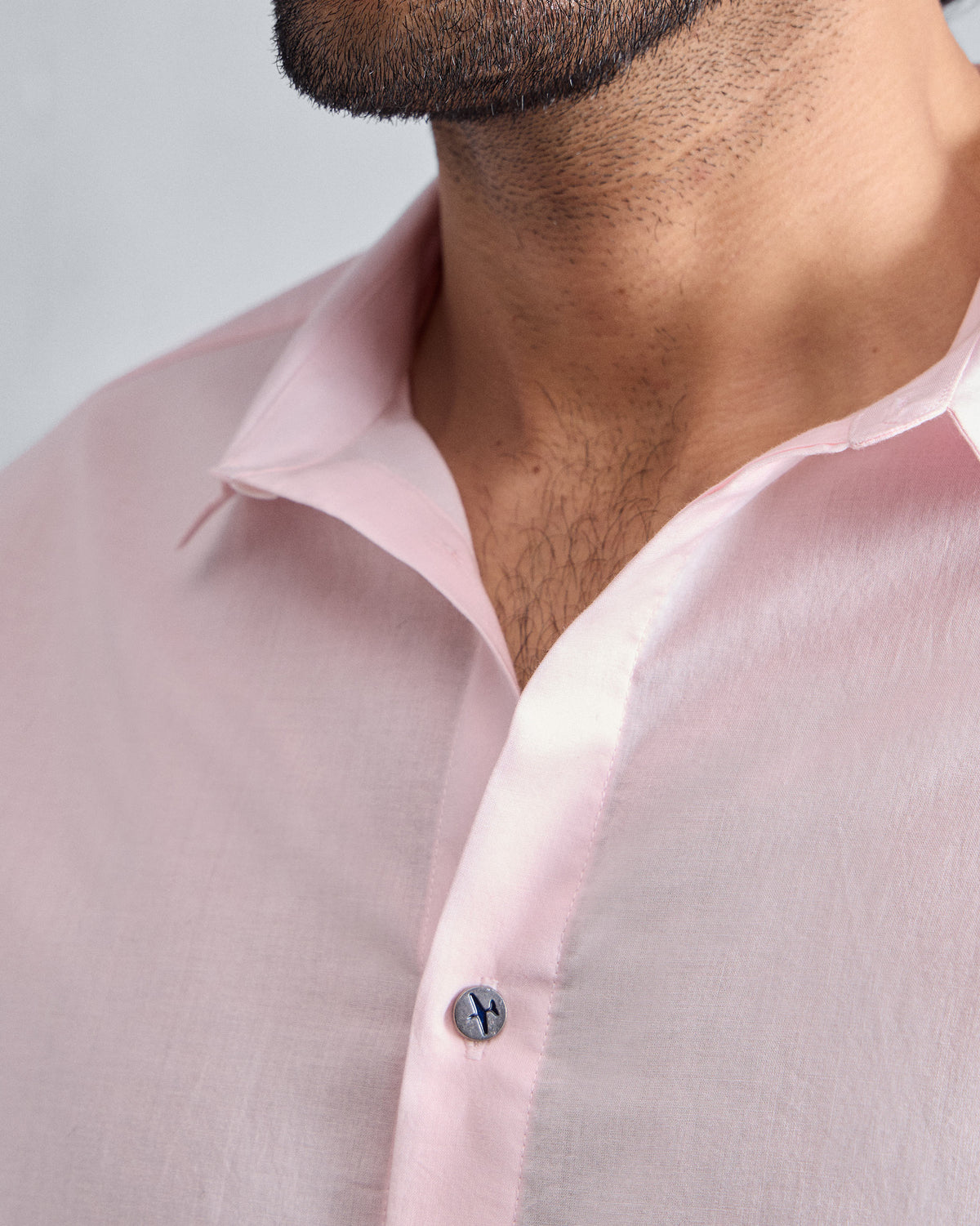 Close-up of a pink Riverine Shirt collar with a dark accent button.