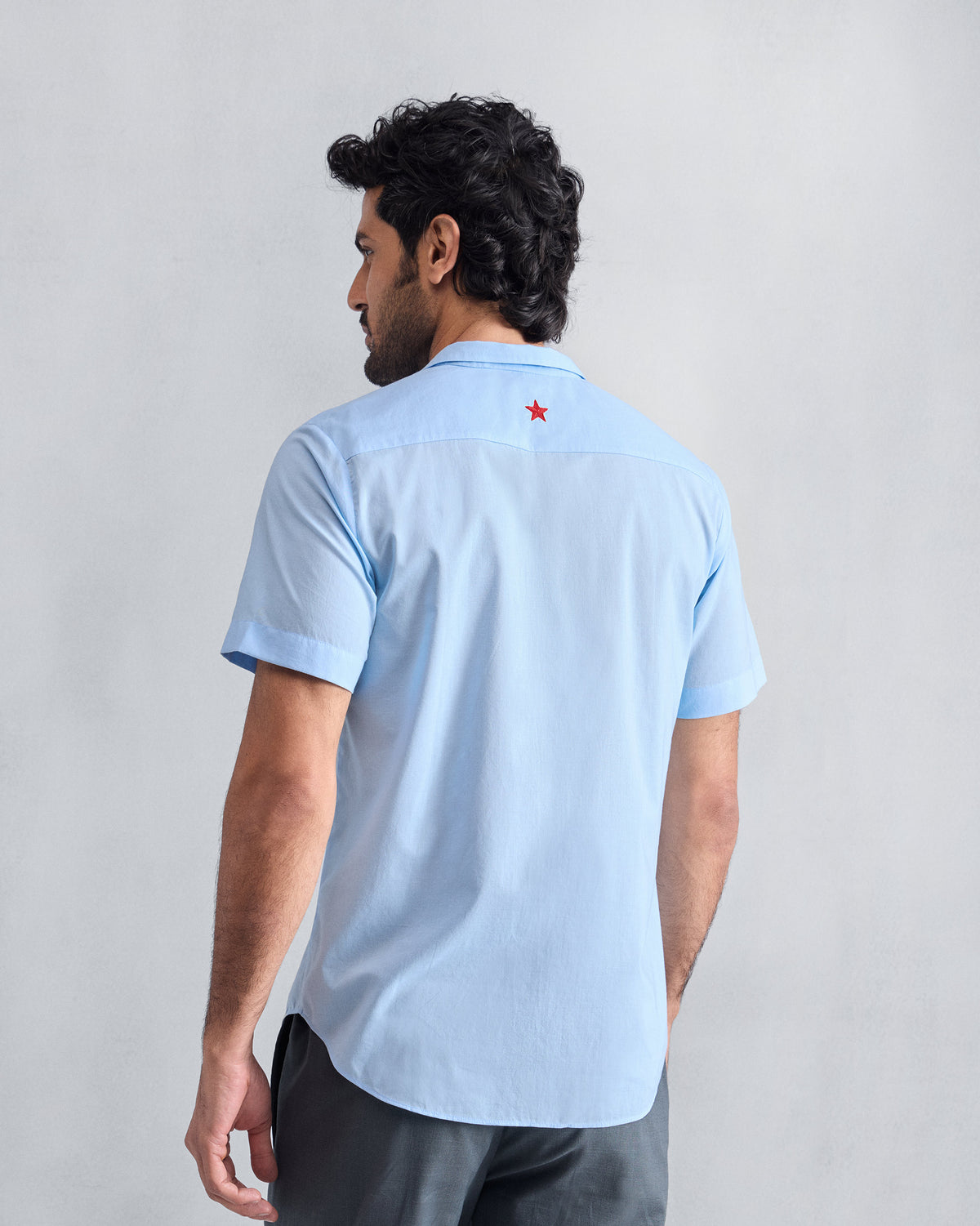 Back of a light blue Riverine shirt showing a small red star.