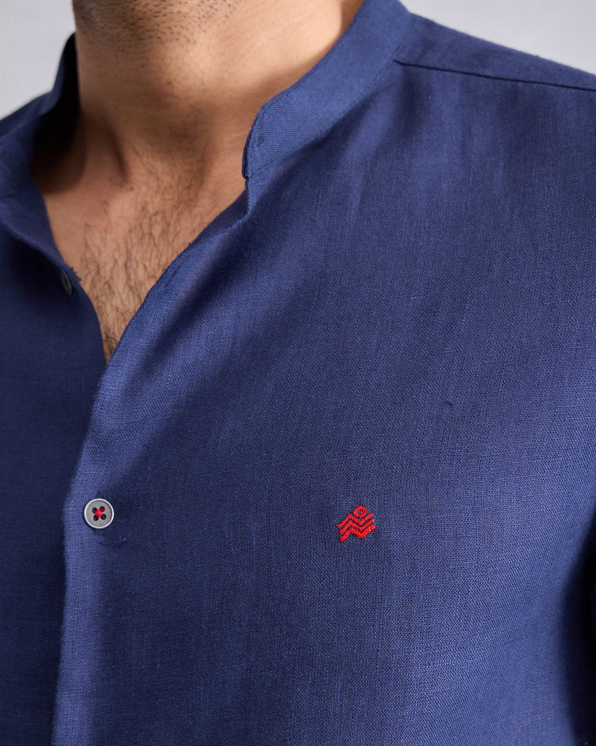 Close-up of a red chest logo on an ink blue Nawab shirt.