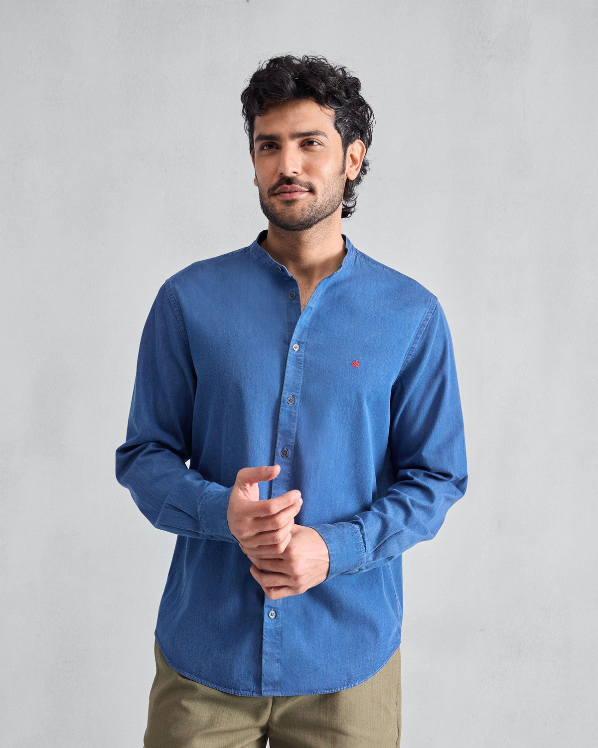 Person wearing a denim Nawab Shirt with a Nehru collar and red chest logomark.