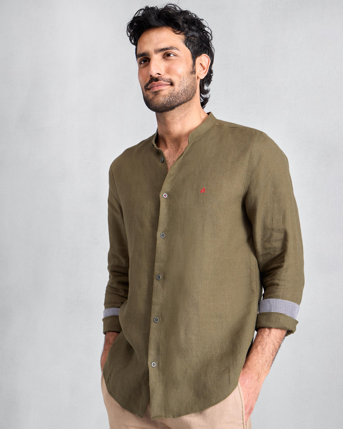 Person wearing an olive Nawab Shirt with a Nehru collar and contrast cuff lining.