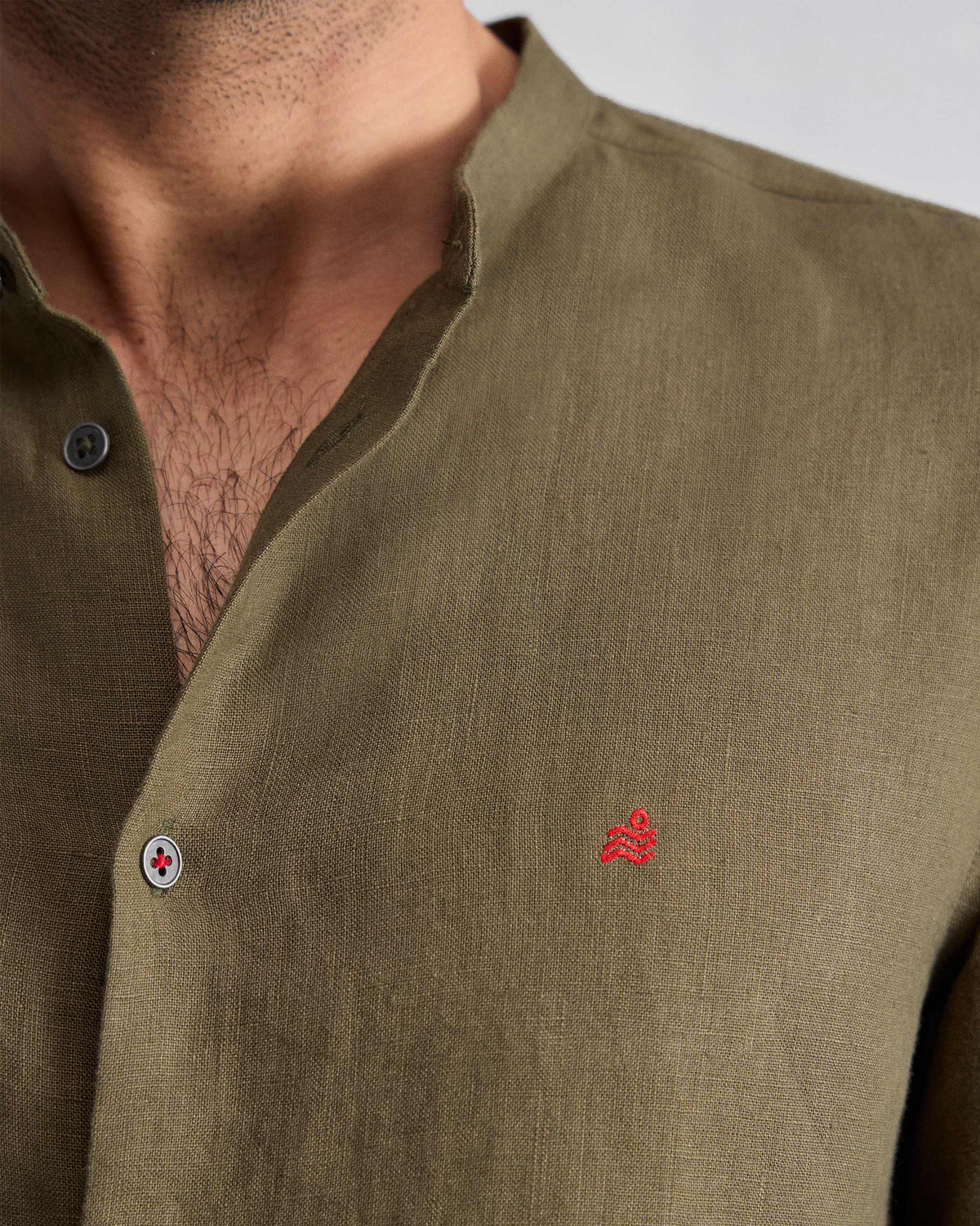 Close-up of an olive Nawab Shirt showing a Nehru collar and red chest logomark.