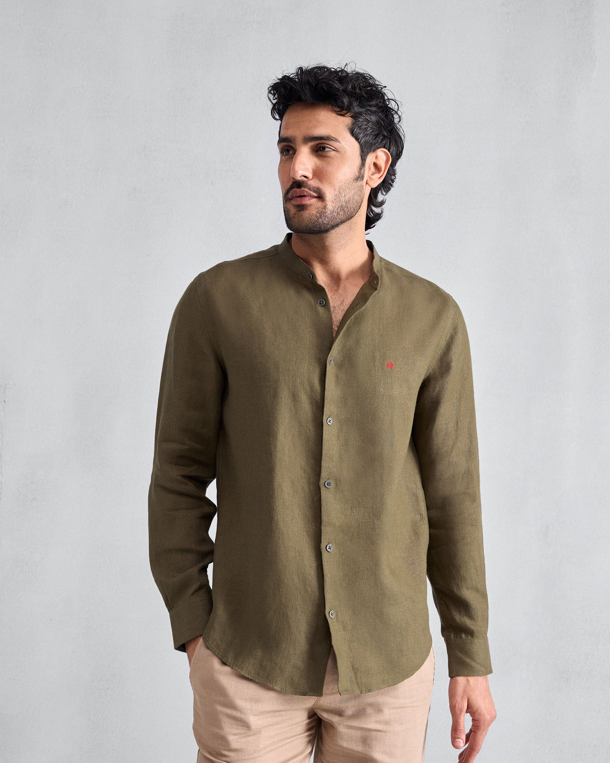 Person wearing an olive Nawab Shirt with a Nehru collar and red chest logomark.