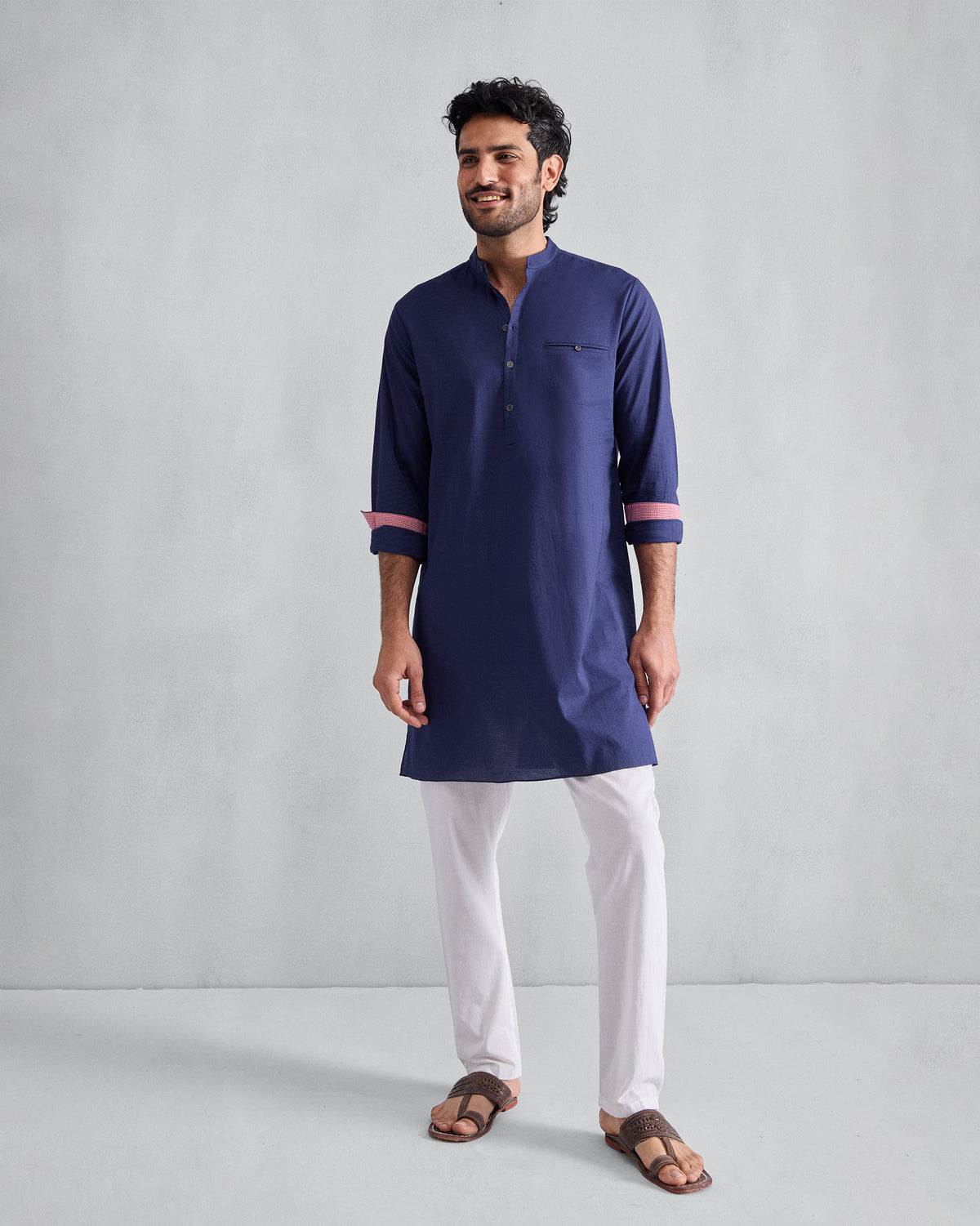 Person wearing an ink blue Pondicherry Kurta with rolled sleeves and pink cuff lining.