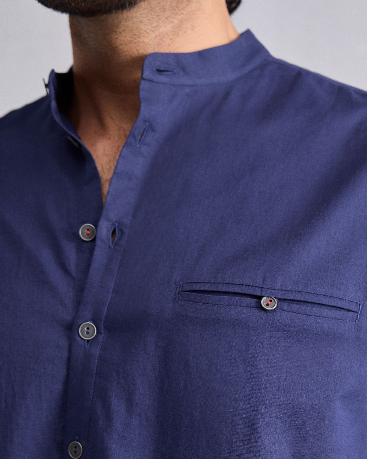 Close-up of an ink blue Pondicherry Kurta showing the mandarin collar and welt pocket.