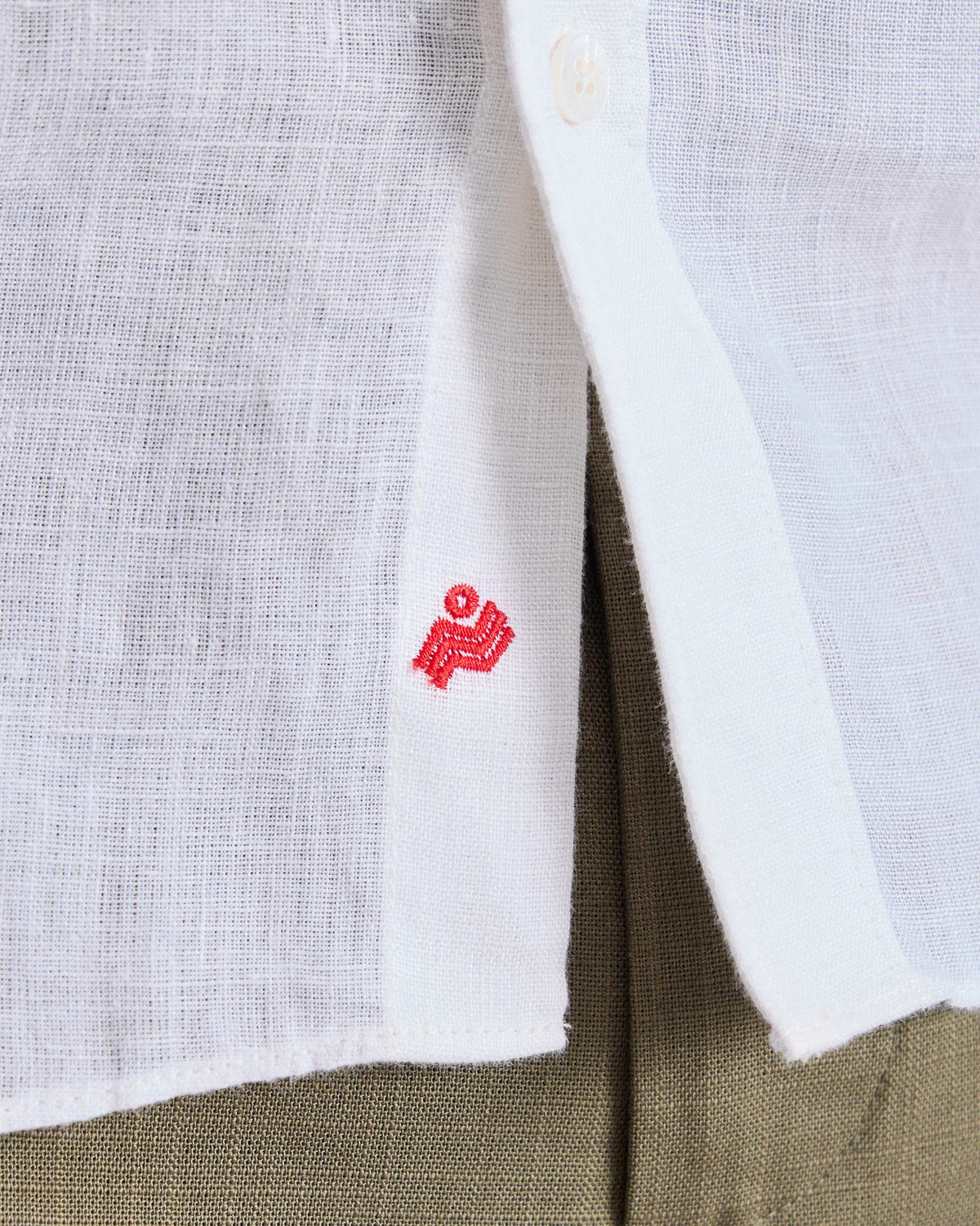Close-up of a white Classic shirt hem with a red Nico logo.