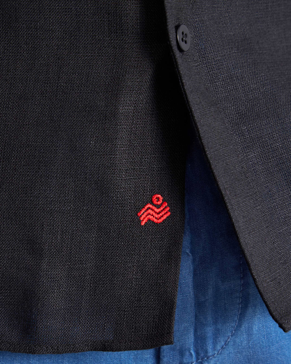 Close-up of a black Classic shirt hem with a red logo.