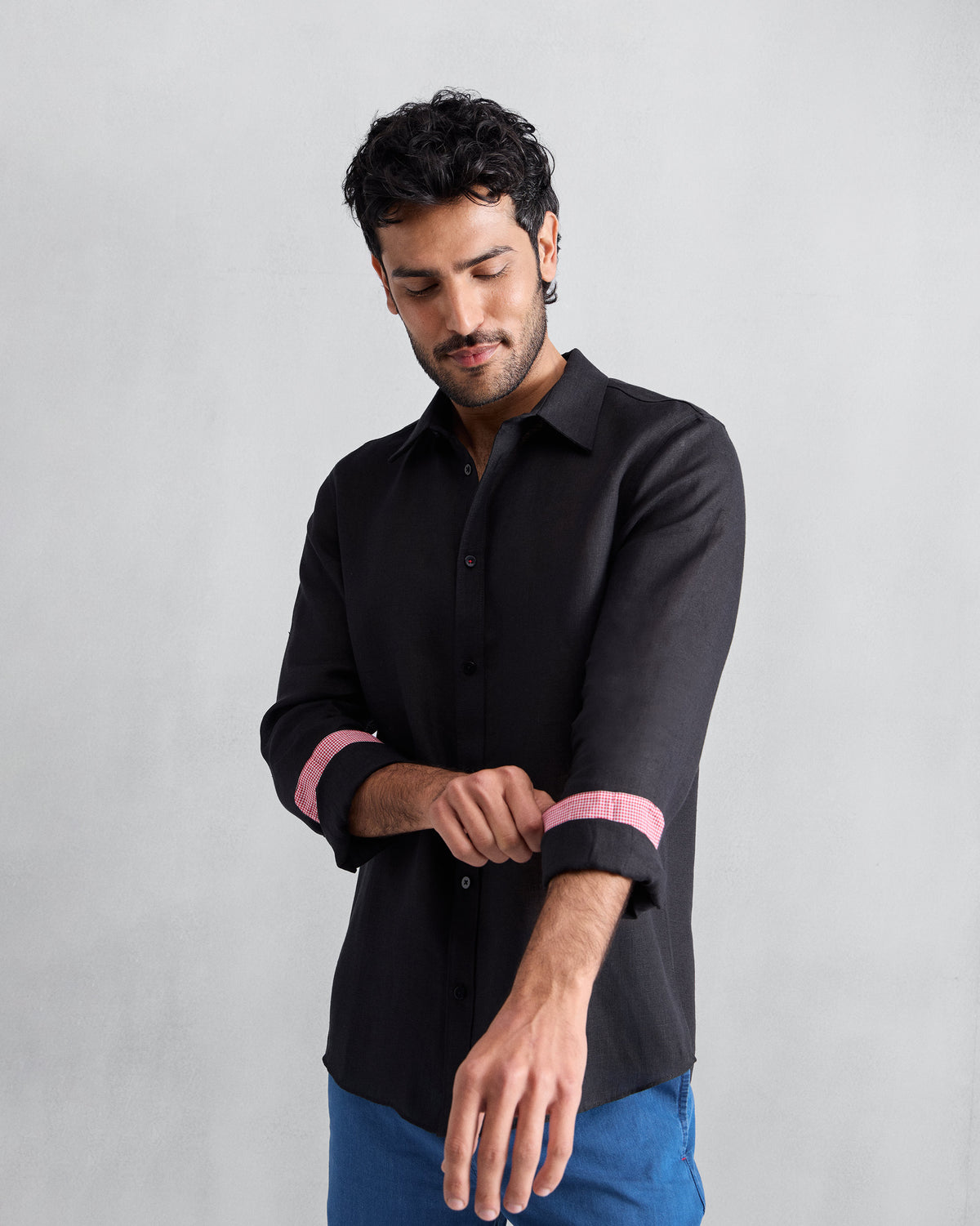 Person wearing a black Classic shirt with pink cuff lining rolled up.