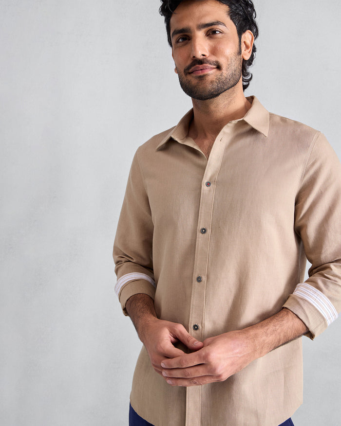 Person wearing a beige Classic shirt with striped cuff lining.