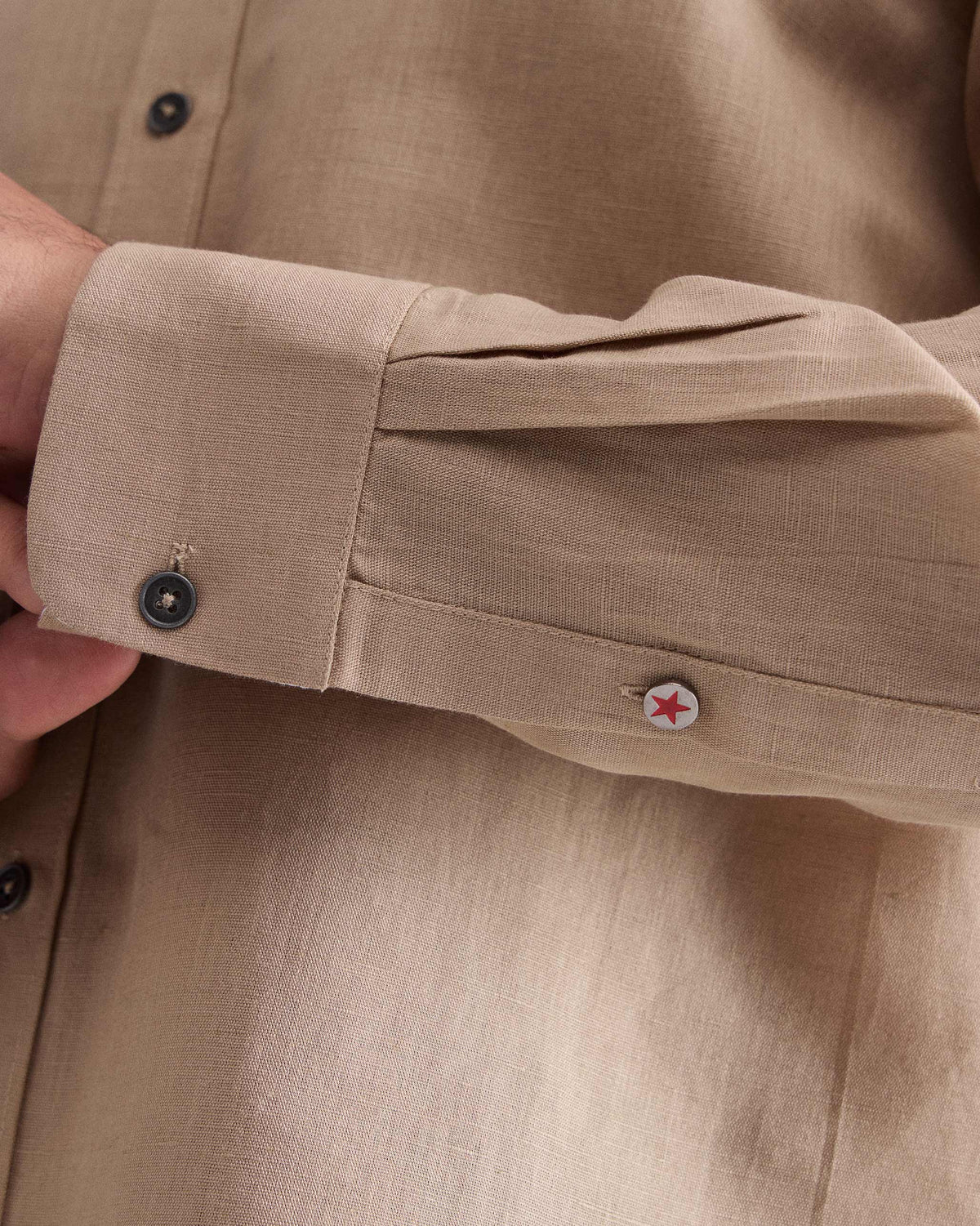 Close-up of a beige Classic shirt cuff with a star button on the placket.