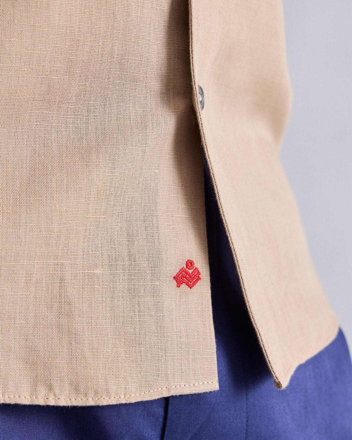 Close-up of a beige Classic shirt hem with a red side logo.