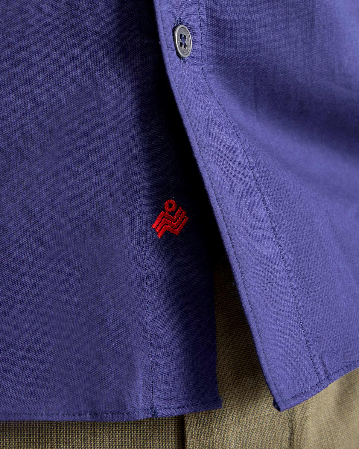 Close-up of an ink blue Classic shirt hem with a red Nico logo.