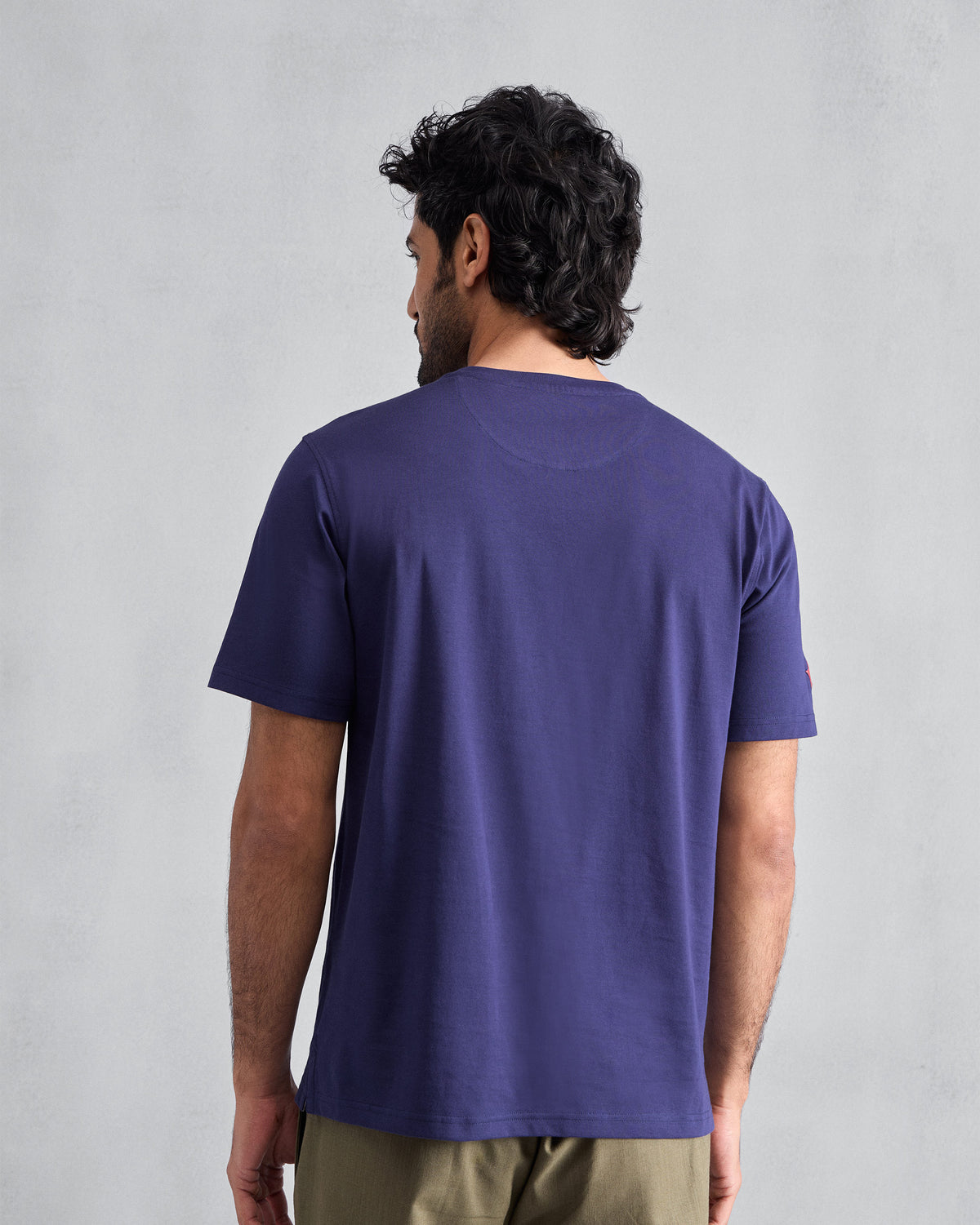 Back of an ink blue Everyday T-shirt worn by a person.