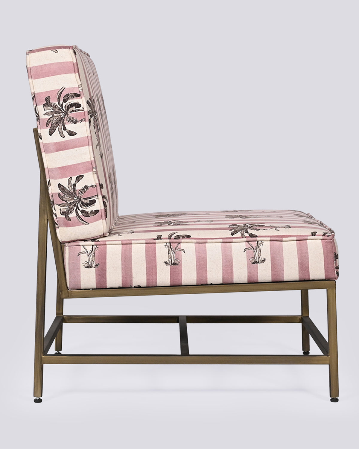 Side view of the Bay Chair showing its brass frame and palm-print cushions.