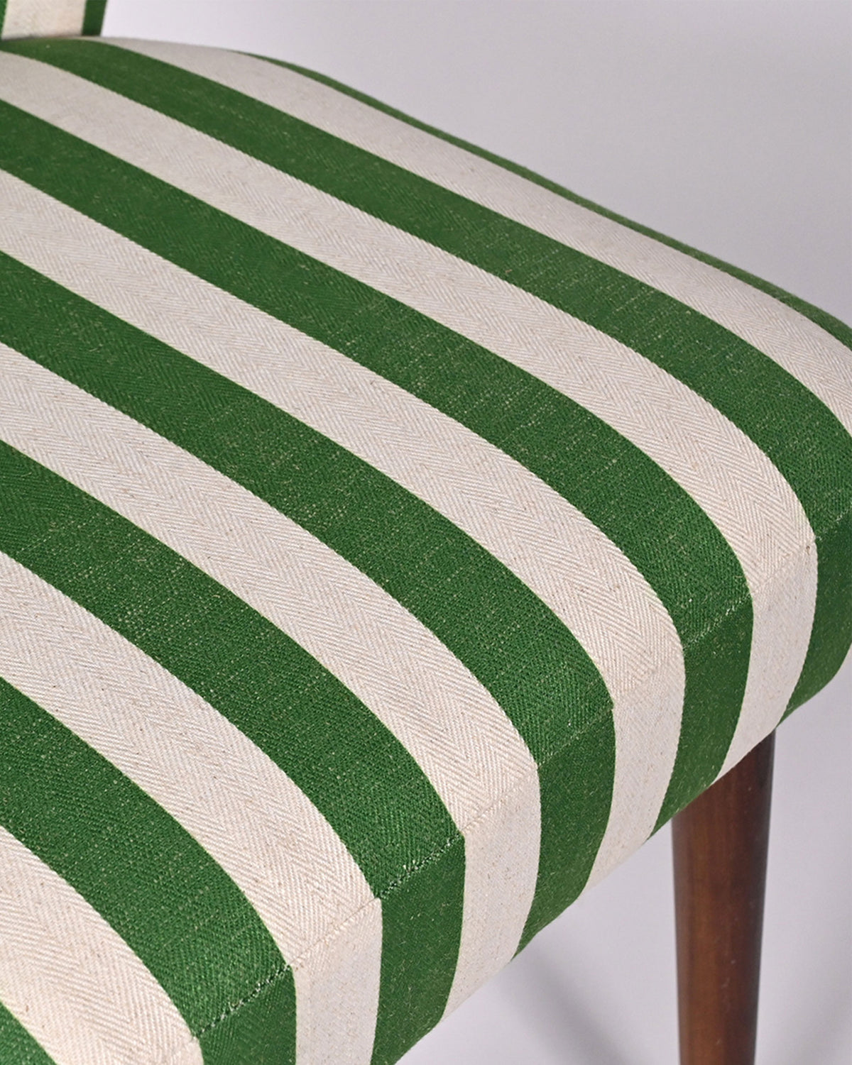 Close-up of the Rain dining chair seat in woven green and cream stripes.