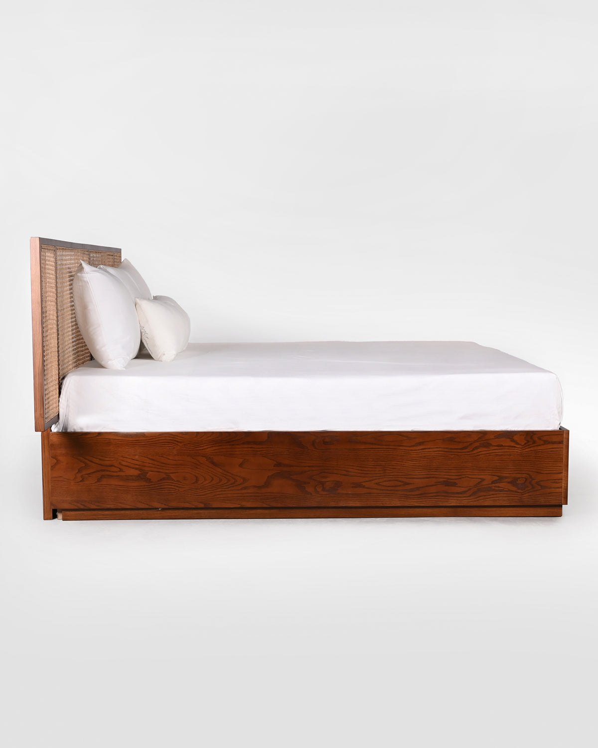 Side view of a Solstice bed with cane headboard and wood platform base.