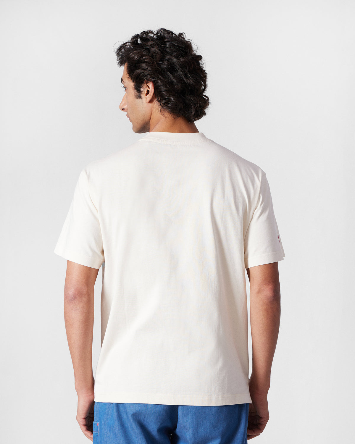 Back of an ivory Bulbul t-shirt worn by a person.