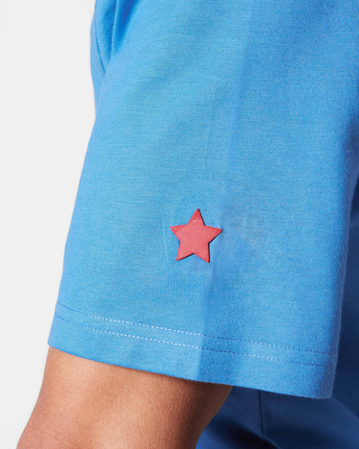 Close-up of a red star on the sleeve of a riverside blue Everyday t-shirt.