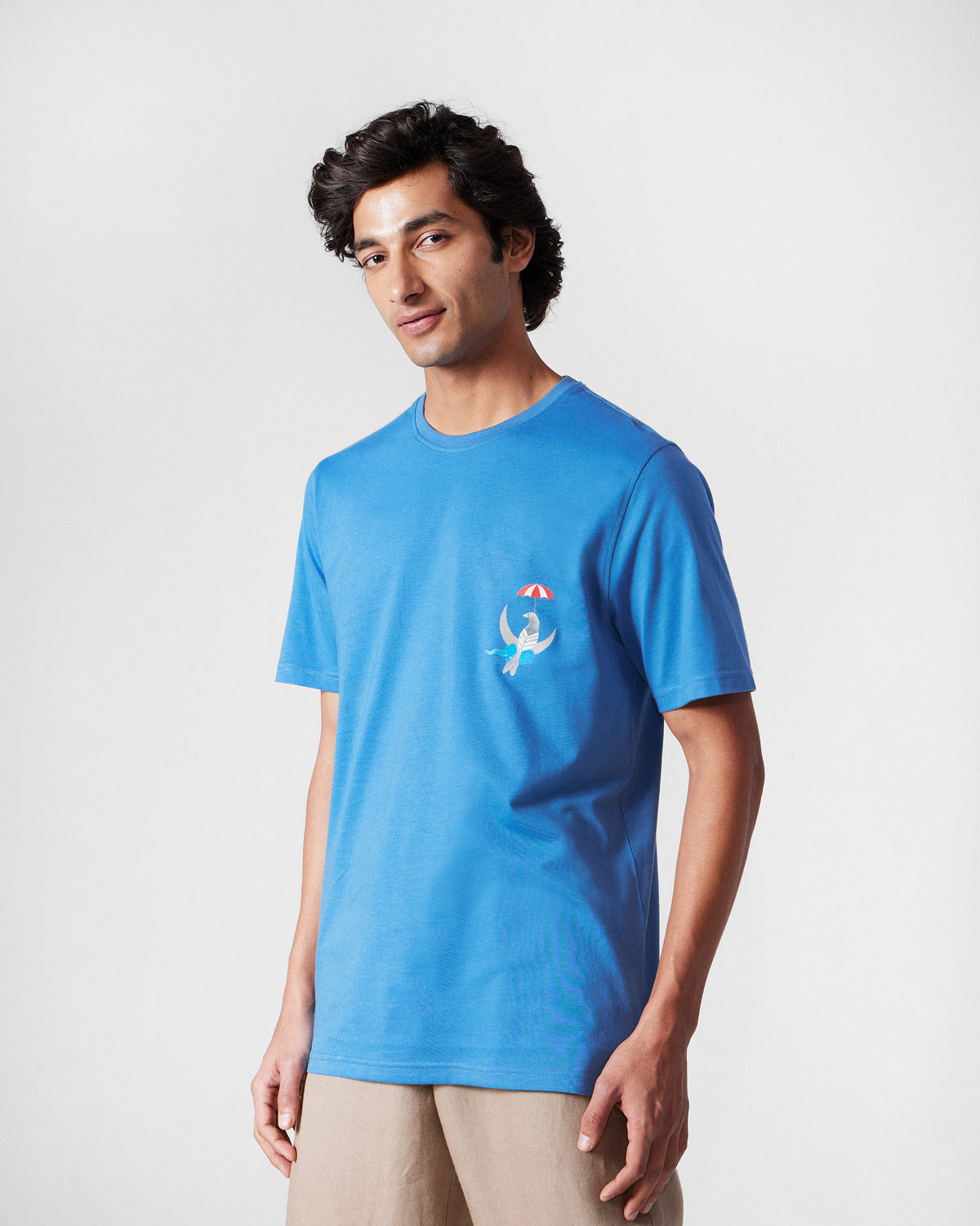 Person wearing a riverside blue Everyday t-shirt with a chest bird motif.