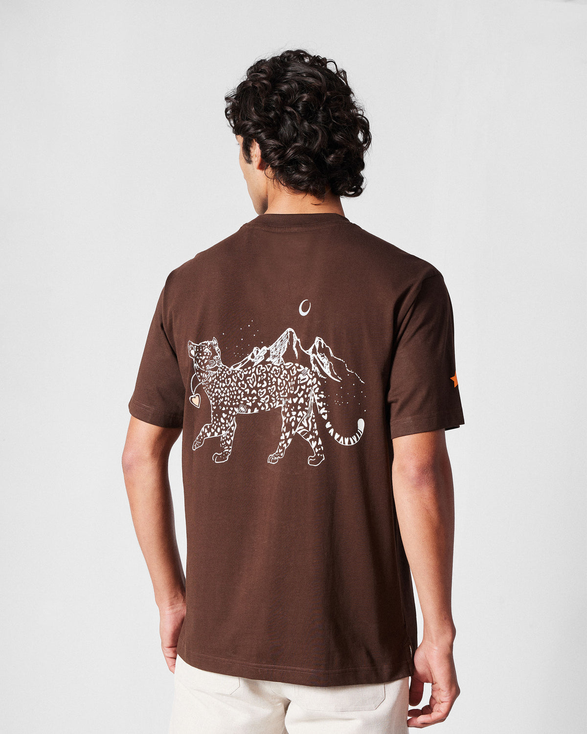 Back of a brown Leap t-shirt with a white leopard and mountain graphic.