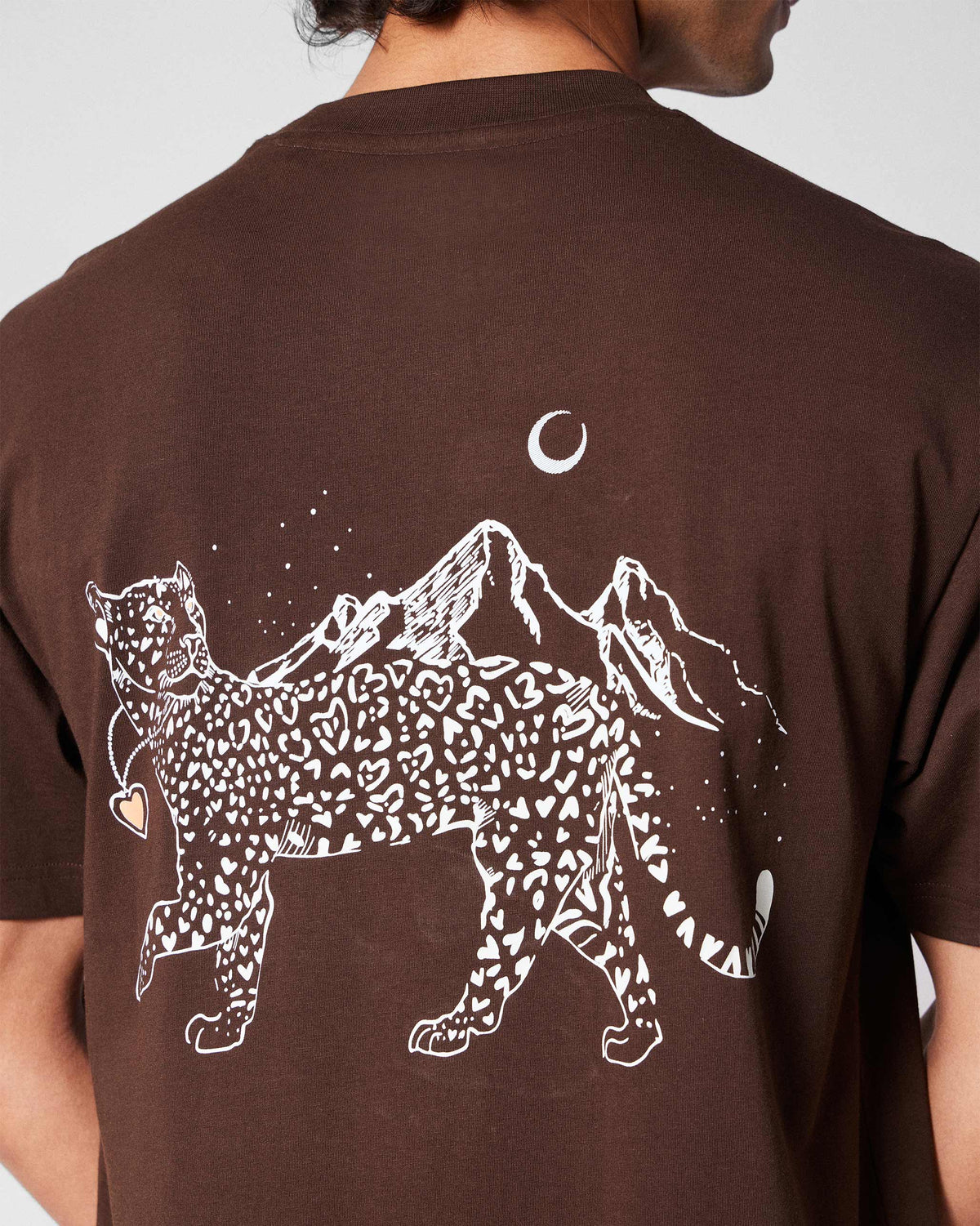 Close-up of a leopard and mountain graphic on a brown Leap t-shirt.