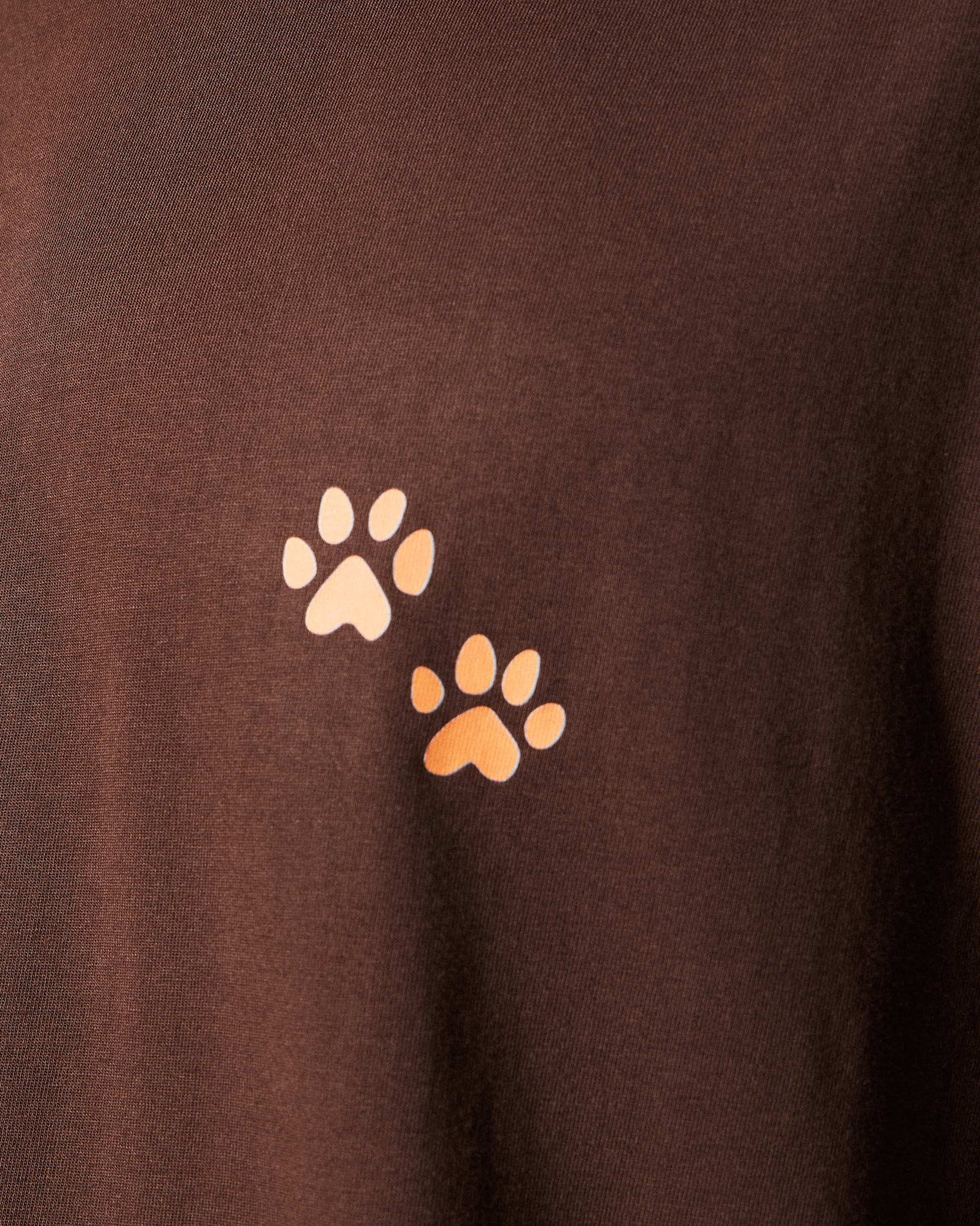 Close-up of peach paw prints on a brown Leap t-shirt.