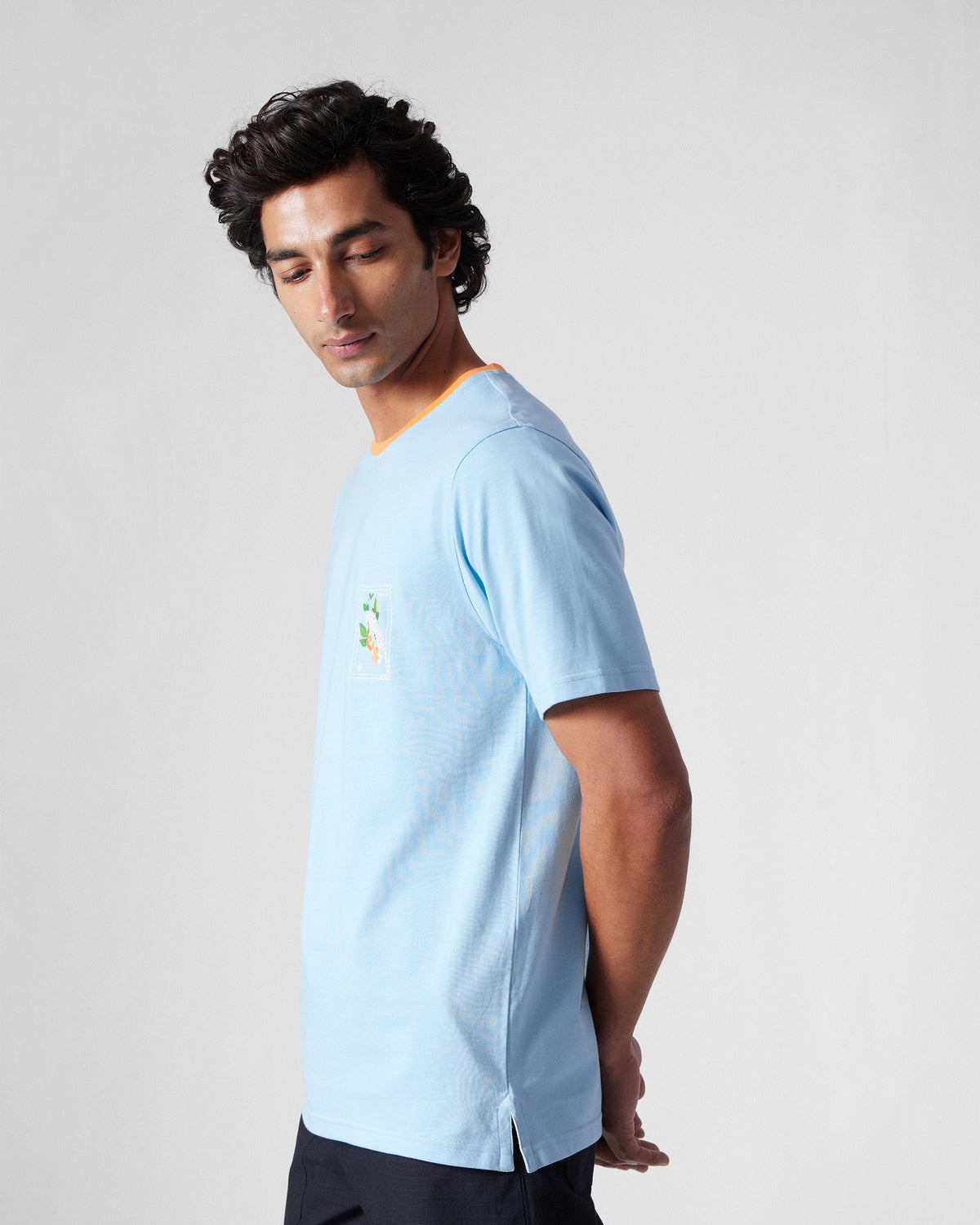 Side view of an ice blue Everyday T-Shirt with an orange collar.