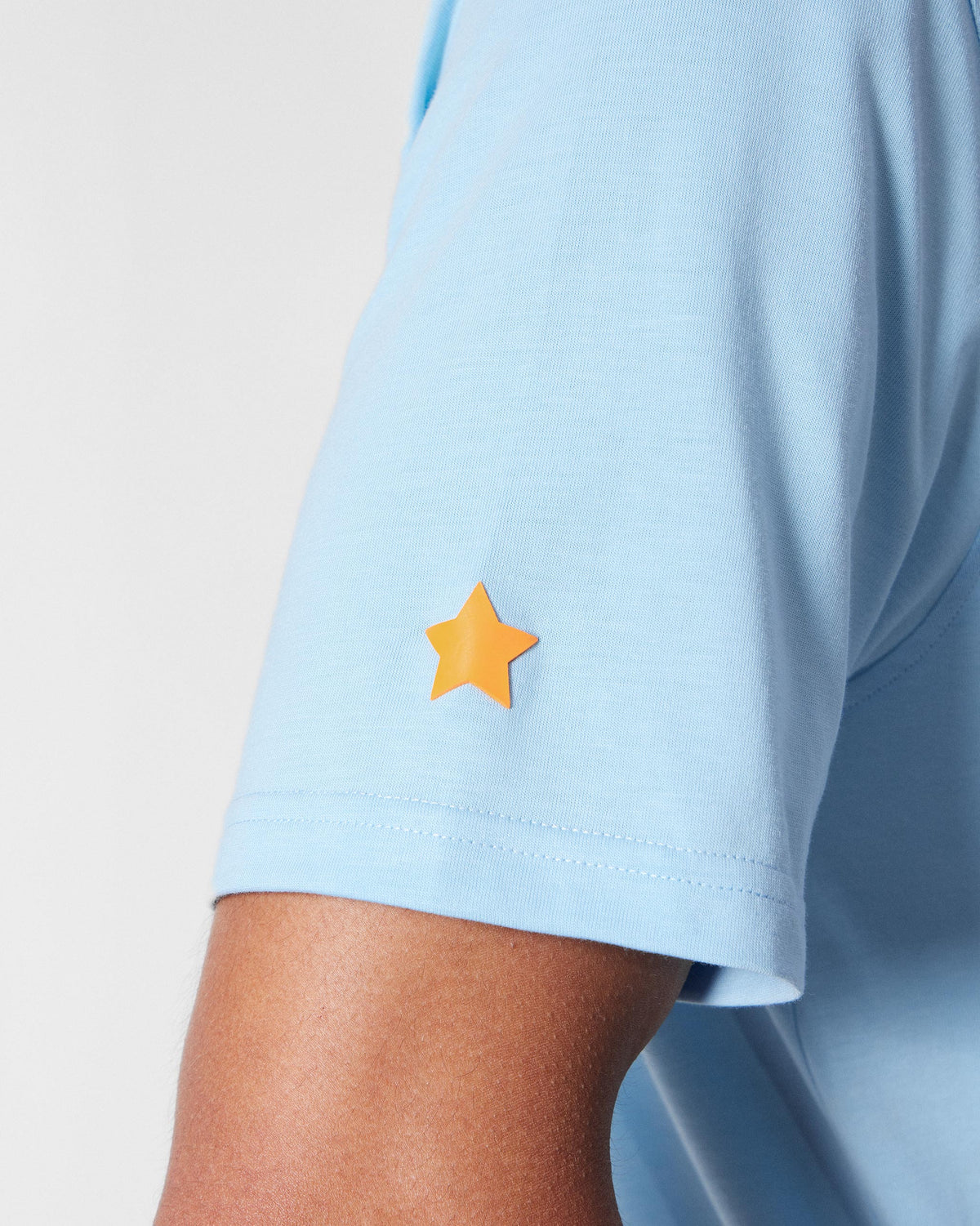 Close-up of an orange star on the sleeve of an ice blue Everyday T-Shirt.