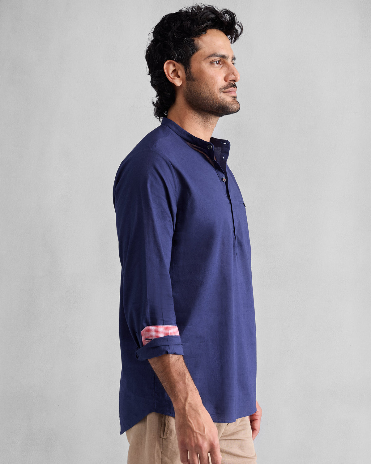 Side view of an ink blue Pondicherry Shirt with rolled sleeves and pink cuff lining.