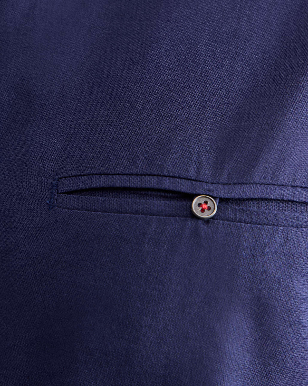 Close-up of a welt pocket with a red-stitched button on an ink blue Pondicherry Shirt.