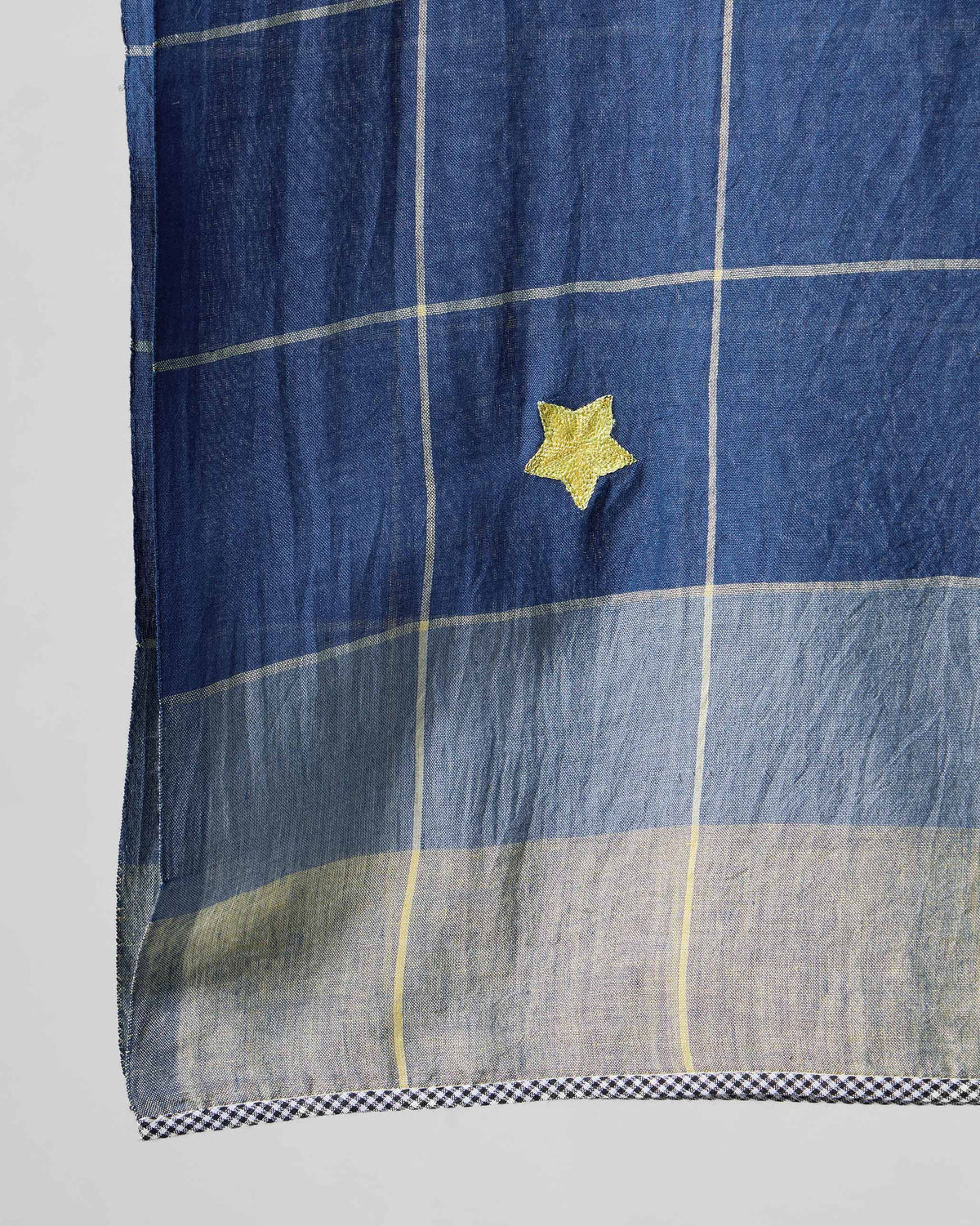 Close-up of Windowpane Checks scarf showing a gold star and pale check lines.