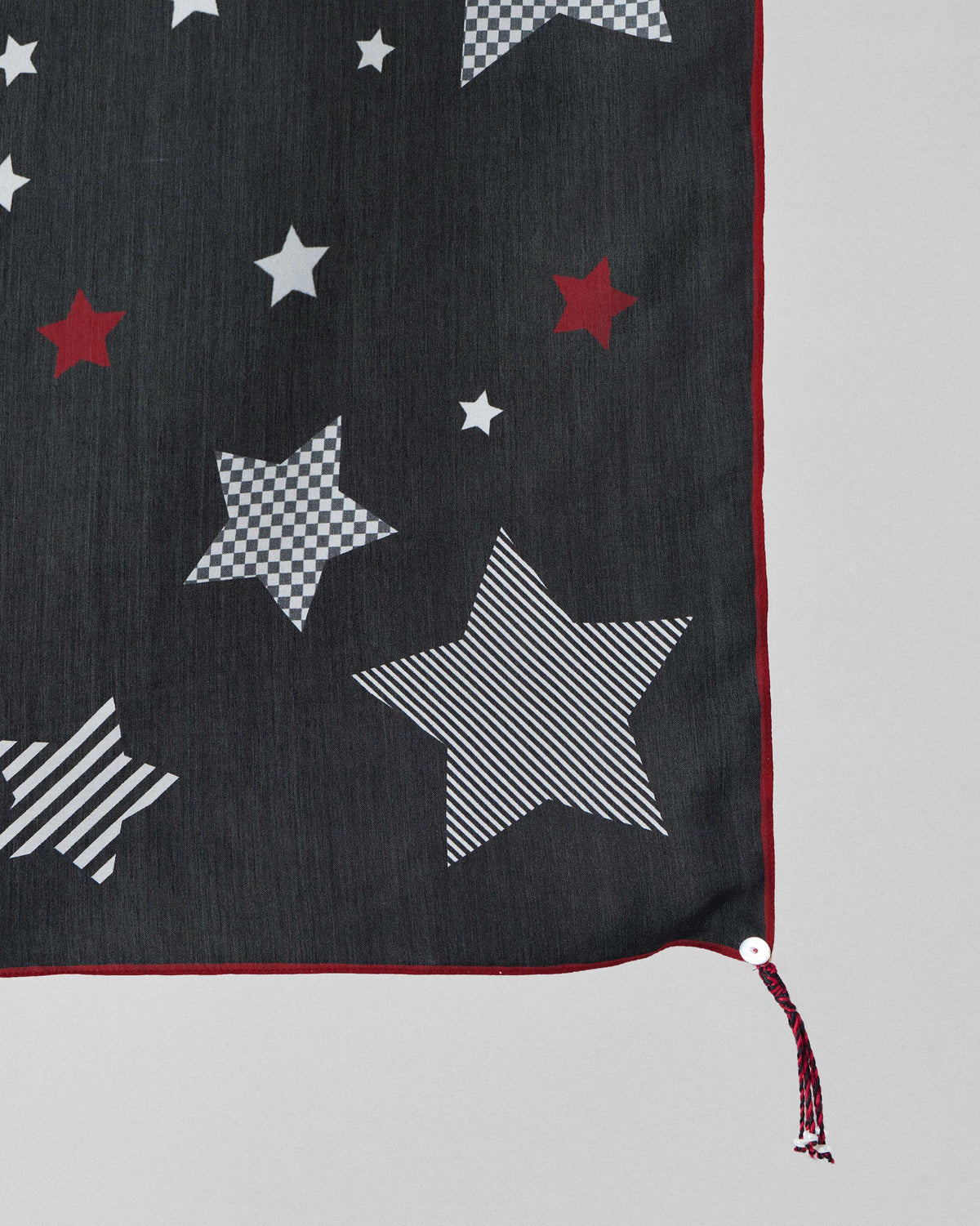 Close-up of the Starry Night Scarf's striped and checked stars with a red tassel.