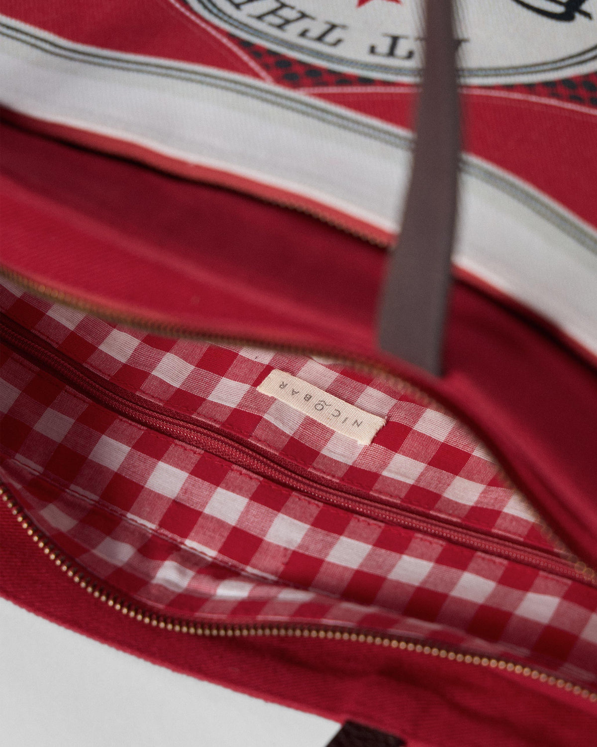 Interior of a Ganges tote with red gingham lining and a zip pocket.