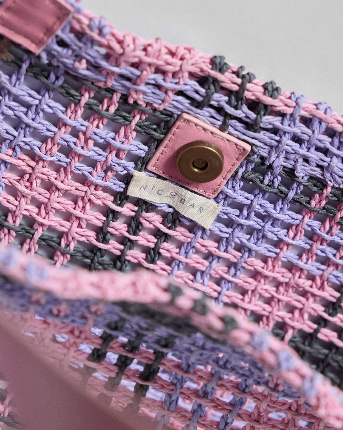 Close-up of Raffle woven tote showing the snap closure and Nicobar label.