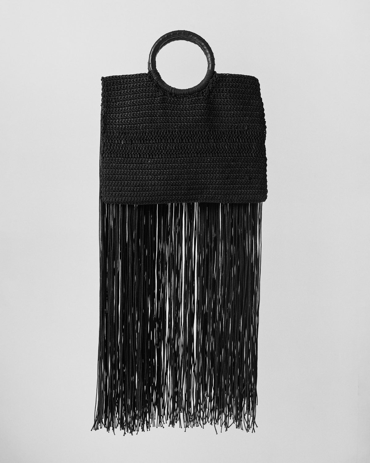 Black braided fringe bag with a circular handle and long fringe.