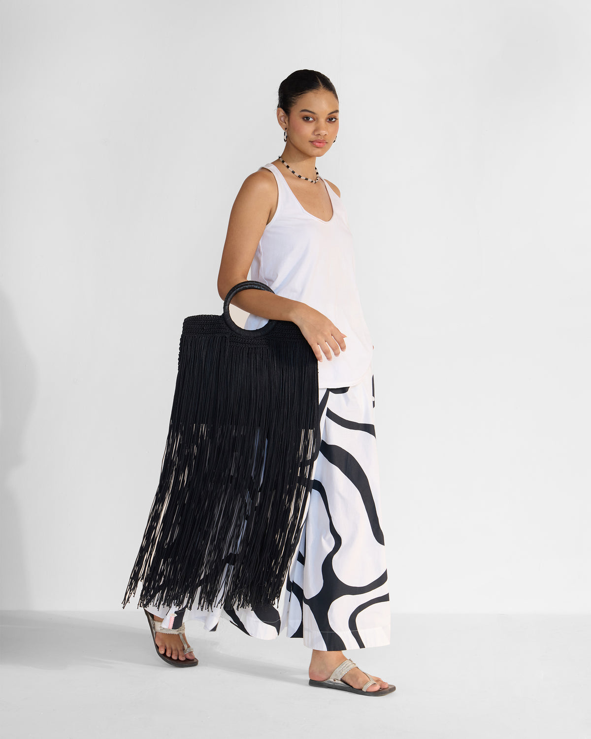 Person carrying a black braided fringe bag with floor-length fringe.