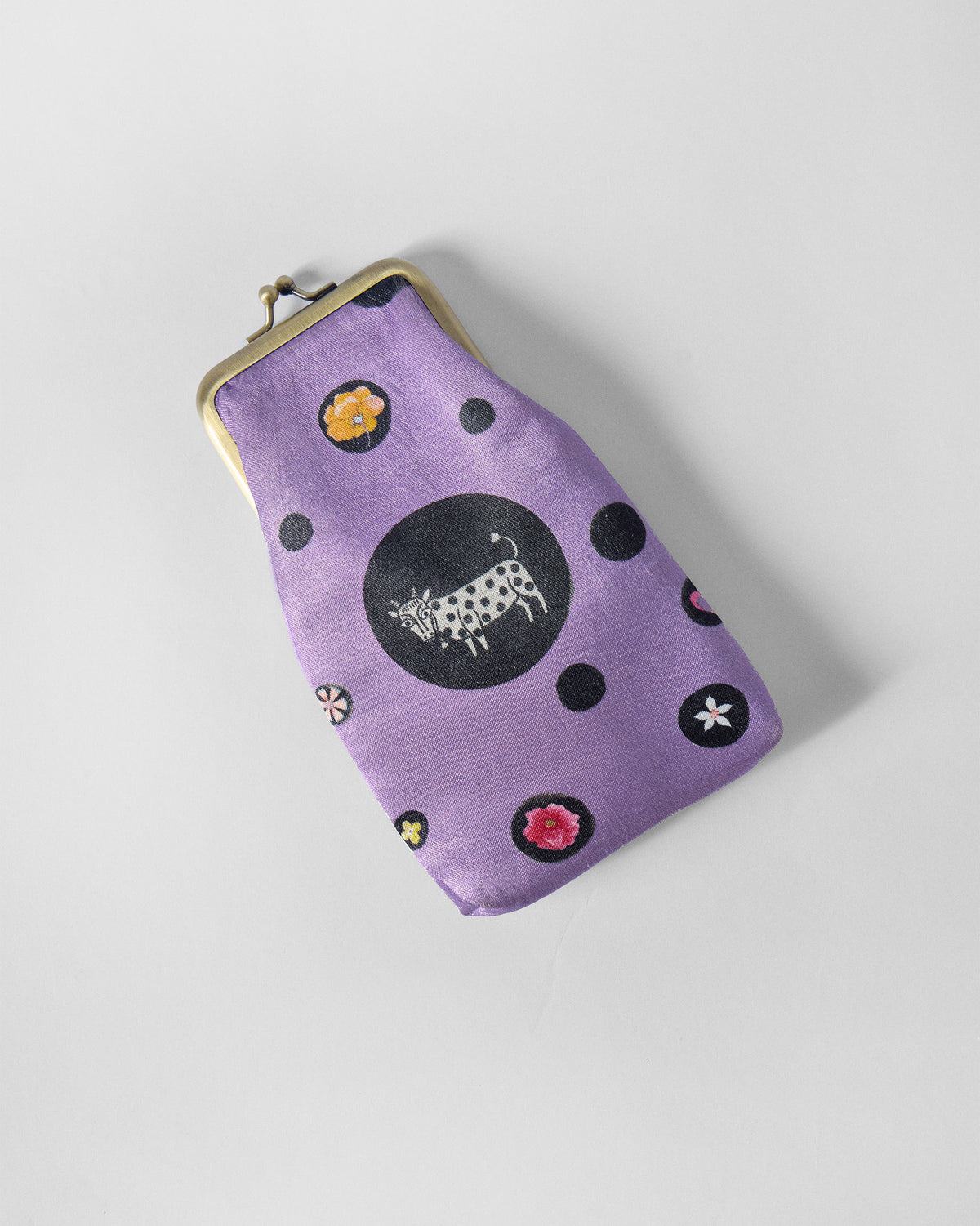 Hana Spec Case angled to show its gold clasp frame and cow motif.
