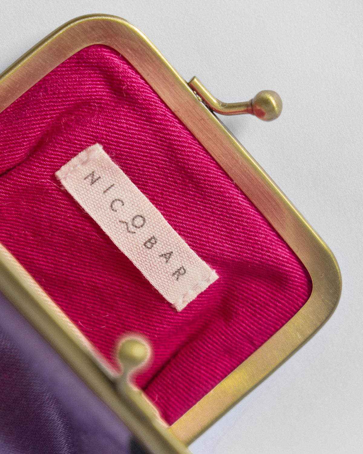 Inside of a Hana Spec Case showing a pink lining and Nicobar label.