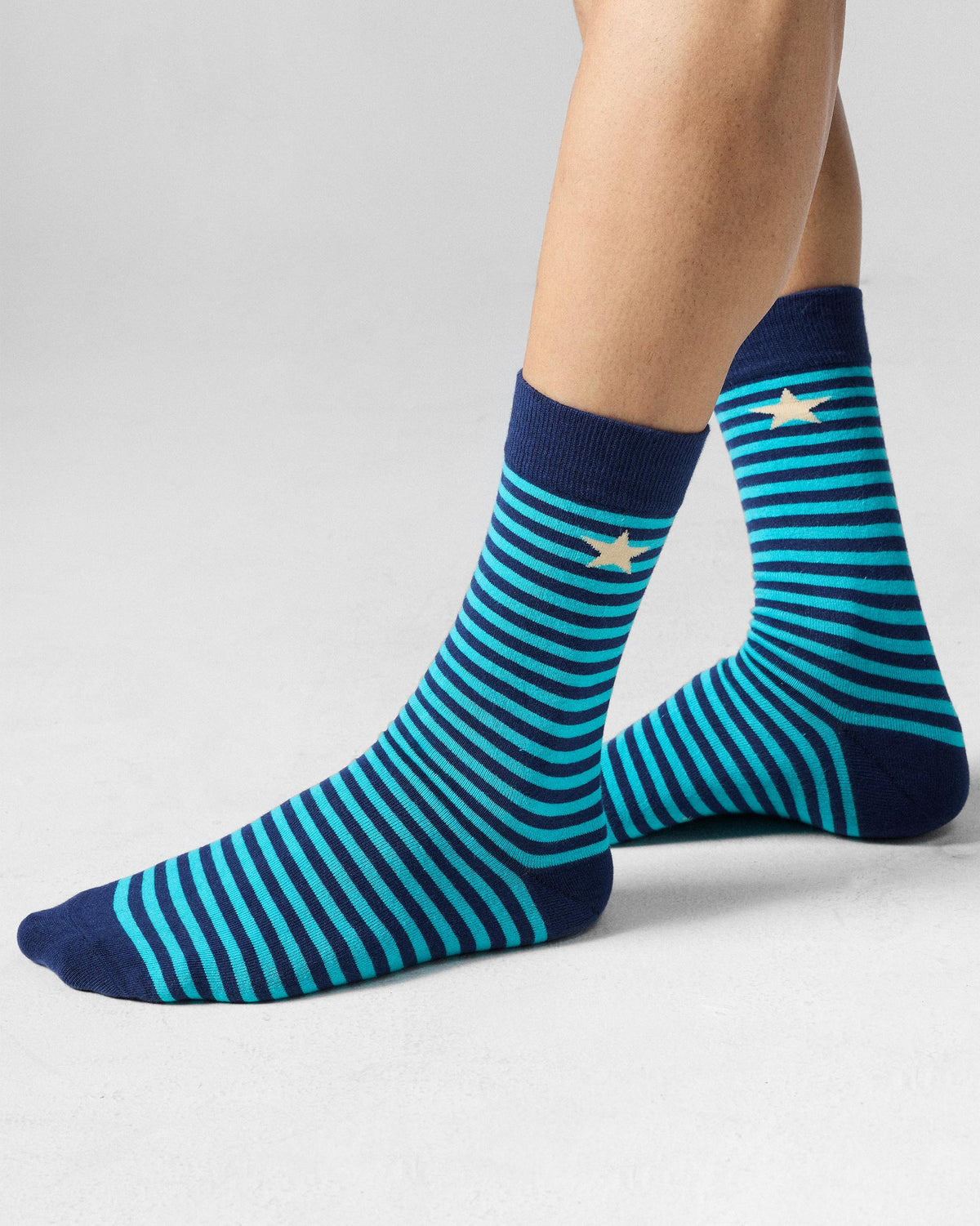 Navy and teal Men's Stride Socks with cream stars worn on the feet.