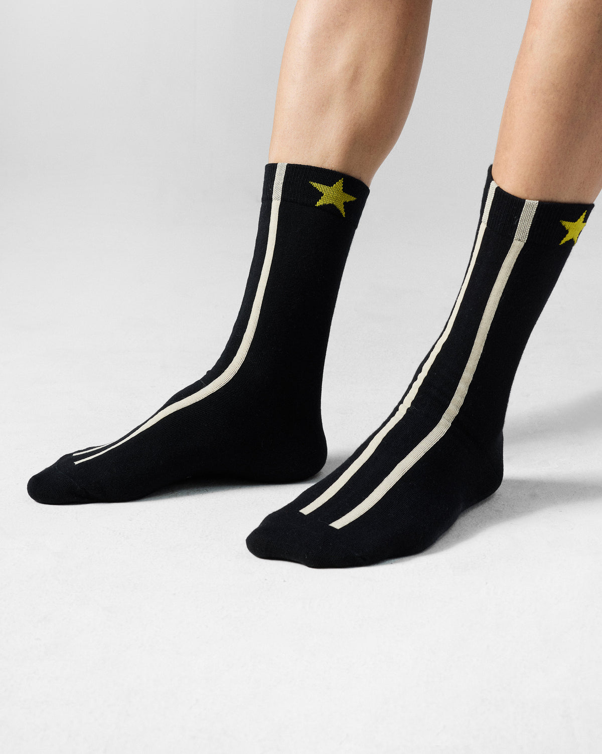 Black Men's Orbit Socks with cream stripes and yellow stars worn.