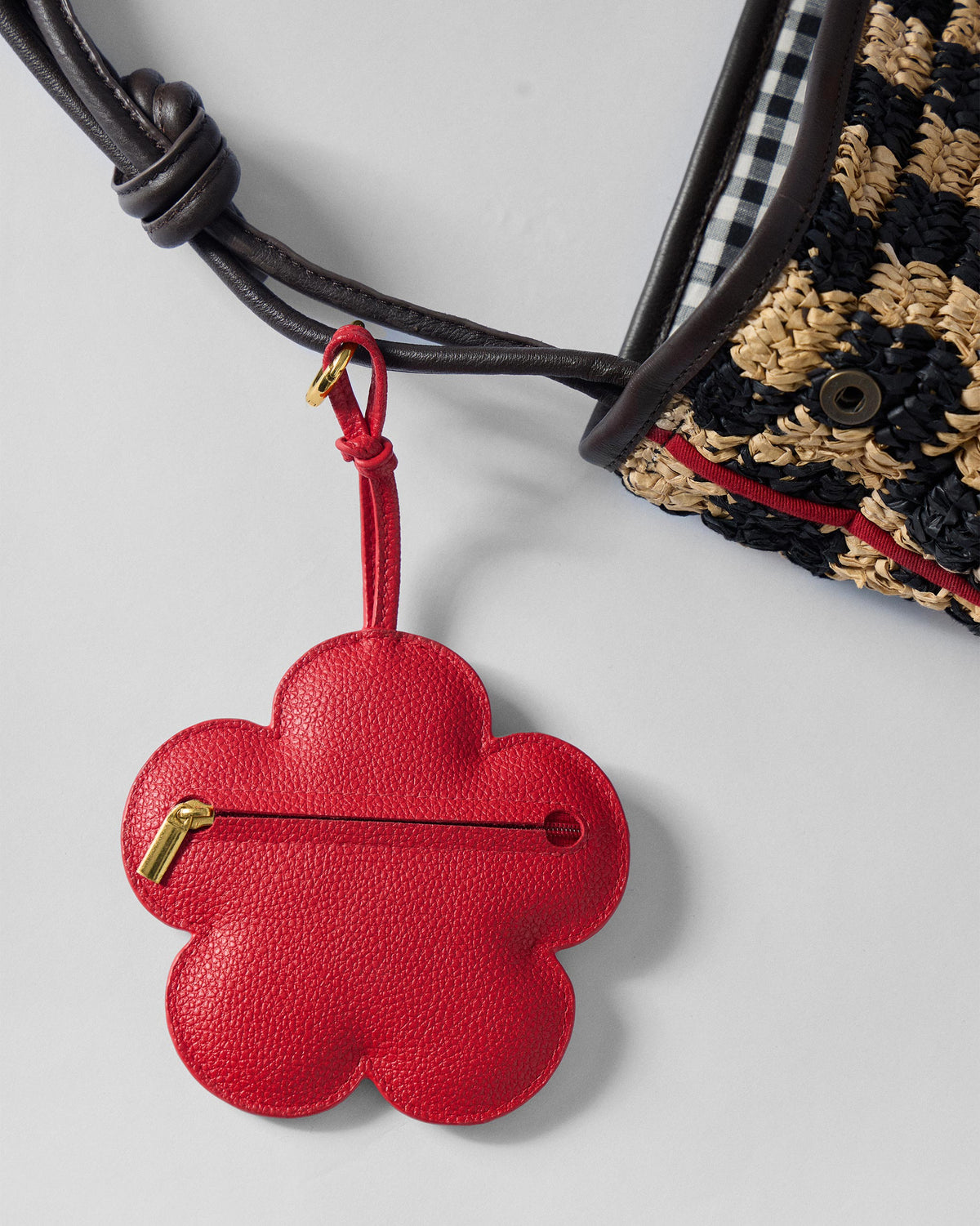 Red Flower Coin Pouch hanging from a woven bag strap, showing its gold clip.