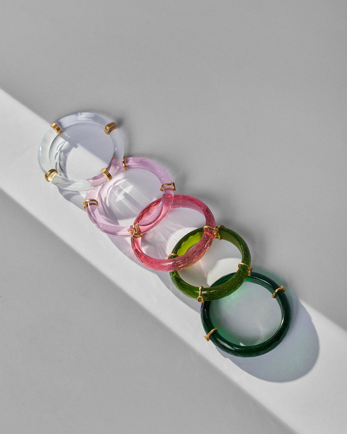 Five Baraat bangles lined in a clear-to-green color gradient with gold accents.